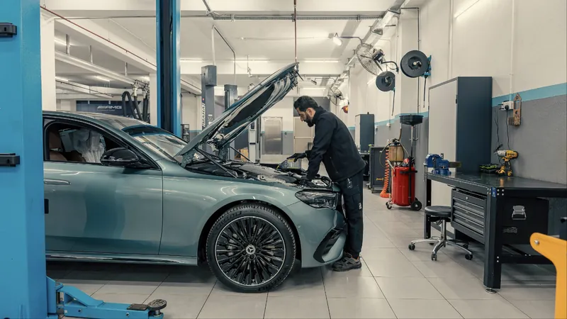 Mehaničar radi ispod otvorene haube automobila u servisnoj radionici
